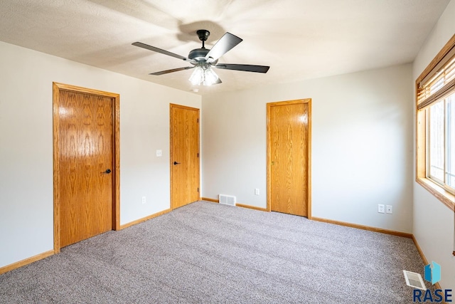 unfurnished bedroom with visible vents, carpet flooring, a ceiling fan, and baseboards