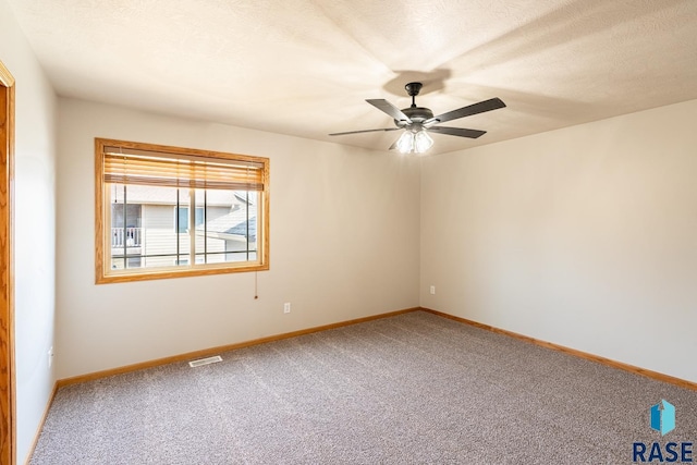 spare room with baseboards, visible vents, a ceiling fan, and carpet