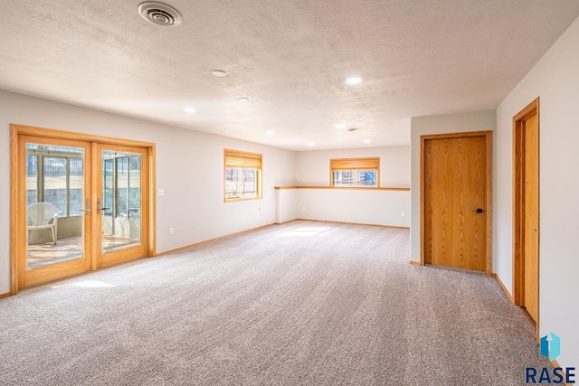 carpeted empty room with a healthy amount of sunlight, visible vents, and baseboards