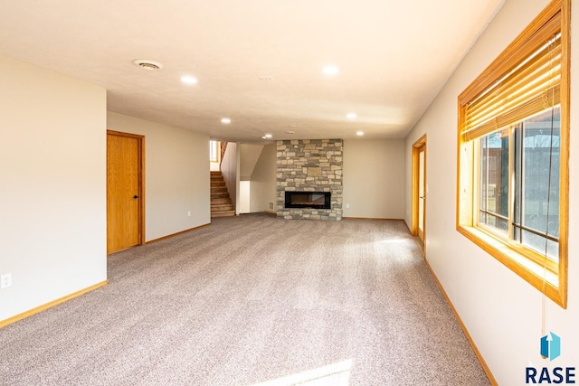 unfurnished living room with baseboards, light colored carpet, stairs, recessed lighting, and a fireplace