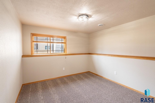 carpeted spare room featuring visible vents, baseboards, and a textured ceiling