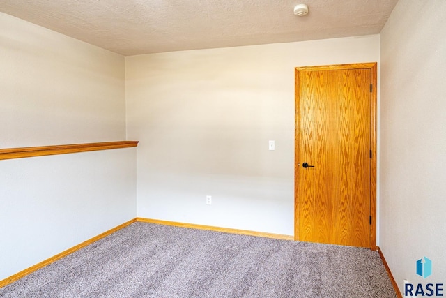 carpeted empty room with baseboards and a textured ceiling