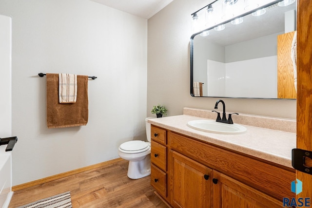 full bath with baseboards, toilet, wood finished floors, and vanity