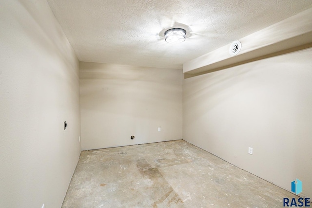 unfurnished room with unfinished concrete flooring and a textured ceiling