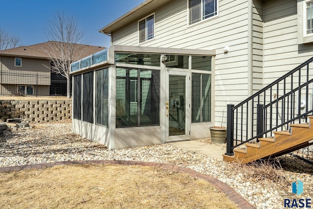 rear view of property with stairs and a sunroom