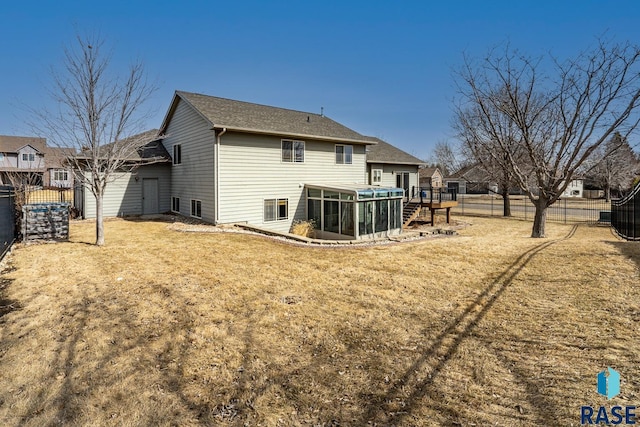 rear view of house featuring a yard, a fenced backyard, and a sunroom