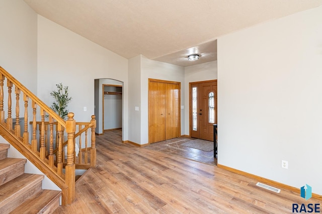 foyer featuring visible vents, arched walkways, baseboards, and light wood-style flooring