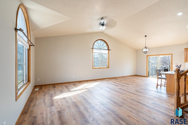 interior space with light wood finished floors, baseboards, a ceiling fan, and lofted ceiling