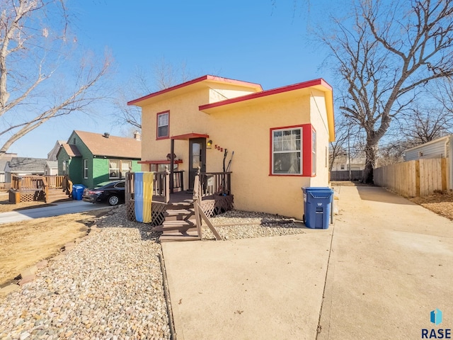 view of front of home featuring stucco siding, a wooden deck, and fence