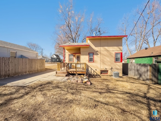 rear view of house featuring central air condition unit and fence