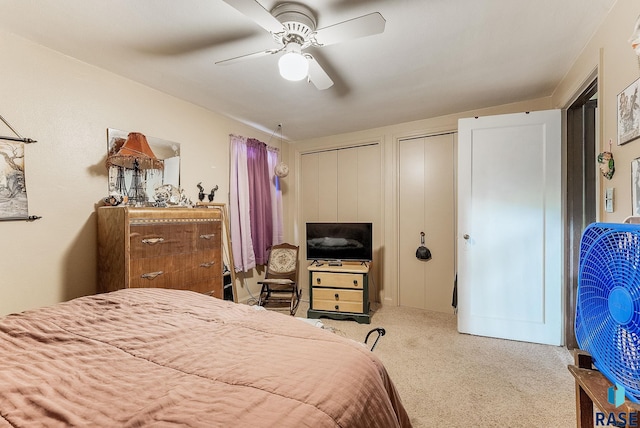 carpeted bedroom featuring two closets and a ceiling fan