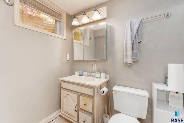 bathroom featuring toilet, vanity, and baseboards