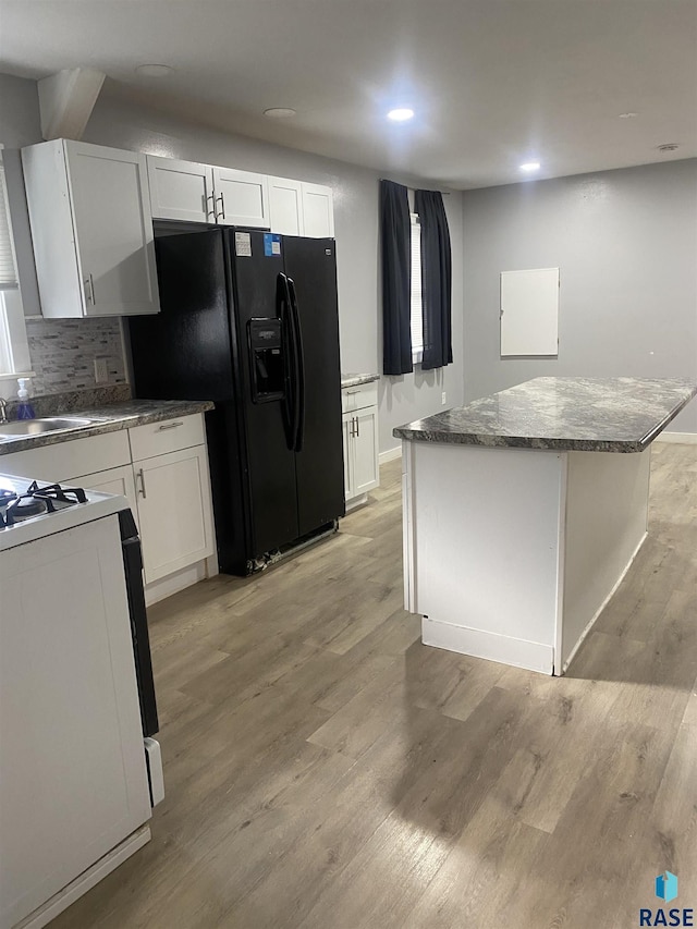 kitchen featuring a sink, range, black fridge with ice dispenser, and light wood-style flooring