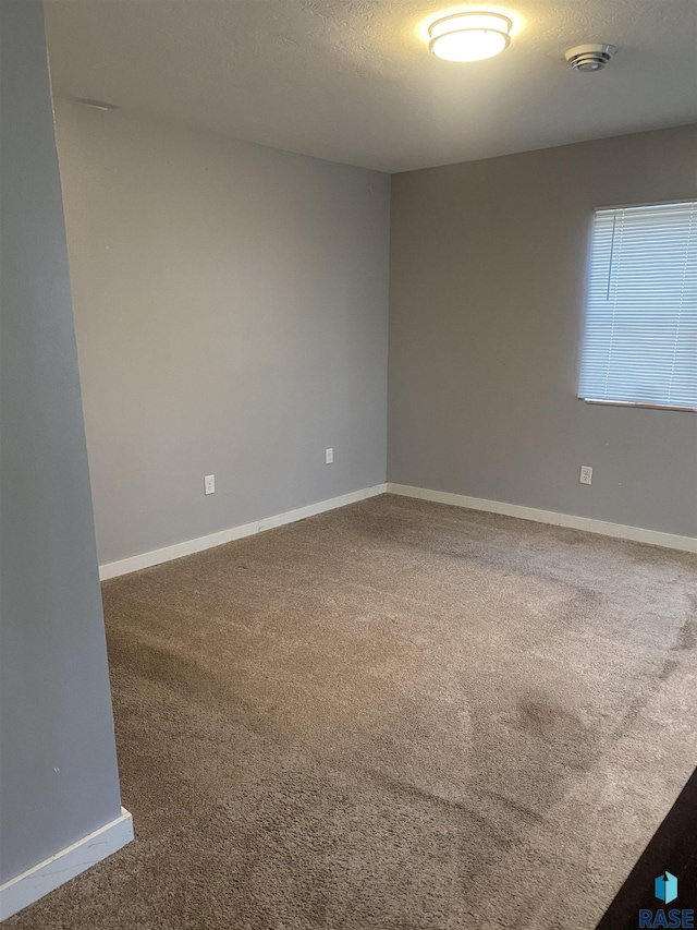 carpeted empty room featuring baseboards and a textured ceiling