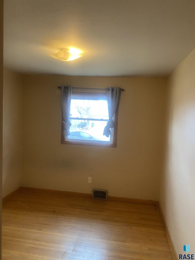 spare room featuring visible vents, baseboards, and light wood-style floors