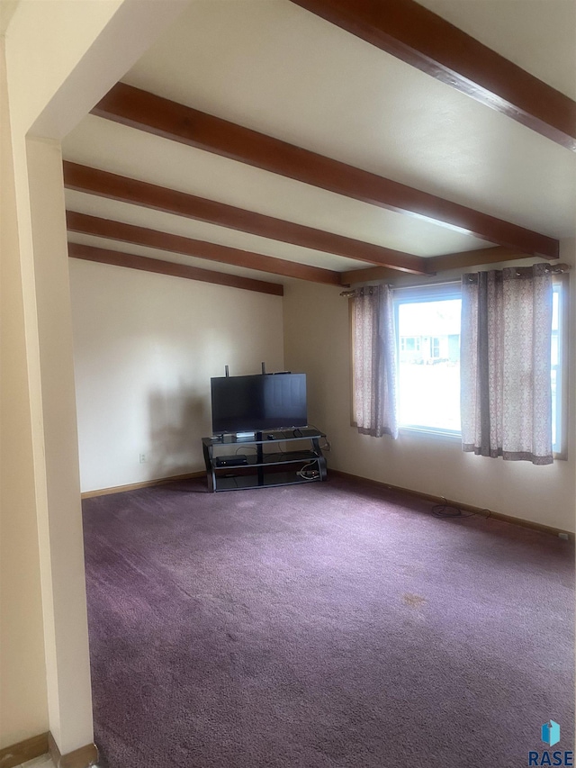 unfurnished living room with baseboards, beam ceiling, and carpet flooring