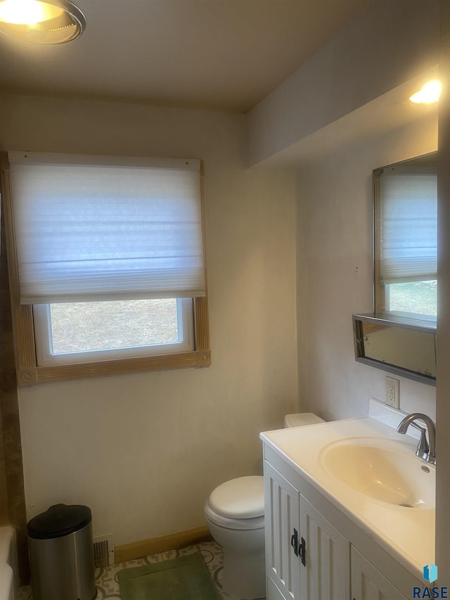 bathroom with toilet, vanity, and baseboards