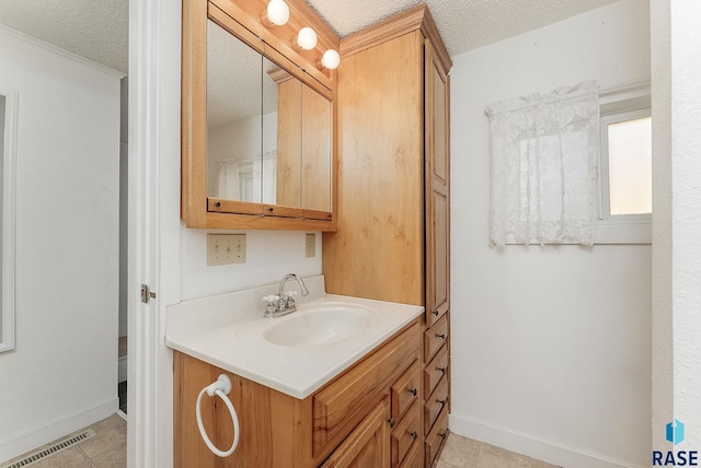 bathroom with tile patterned floors, visible vents, a textured ceiling, baseboards, and vanity