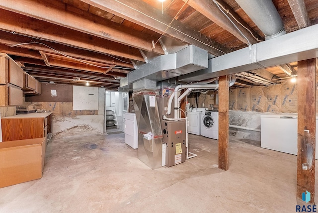 unfinished basement featuring washer and dryer, fridge, heating unit, and stairway