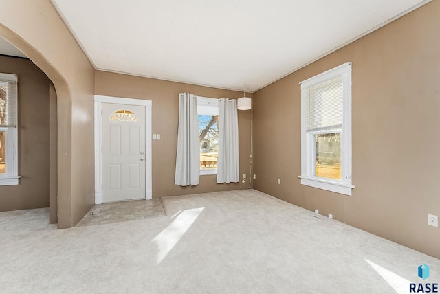 carpeted entrance foyer featuring arched walkways