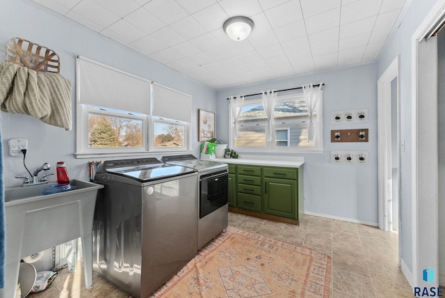 clothes washing area featuring a sink, baseboards, cabinet space, and washing machine and clothes dryer