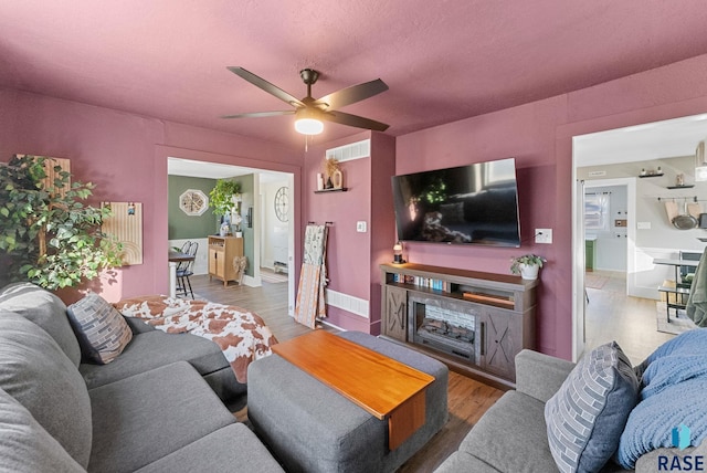 living area with visible vents, wood finished floors, and a ceiling fan