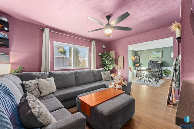 living room featuring a textured ceiling, a ceiling fan, and wood finished floors