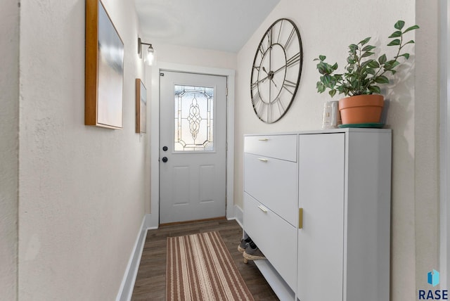 doorway with dark wood finished floors and baseboards