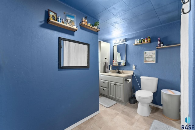 bathroom with toilet, vanity, and baseboards