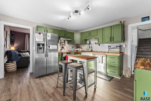 kitchen with green cabinetry, appliances with stainless steel finishes, wood finished floors, and under cabinet range hood