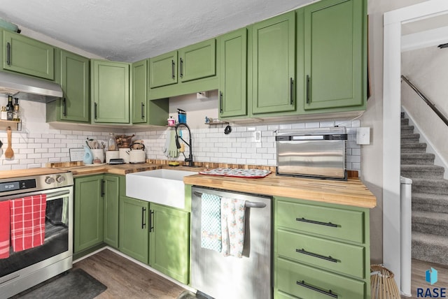 kitchen featuring wooden counters, a sink, stainless steel appliances, dark wood-type flooring, and under cabinet range hood