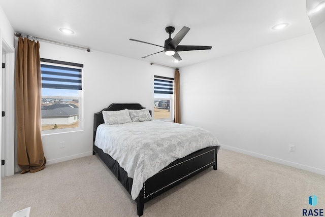 bedroom with multiple windows, light colored carpet, baseboards, and ceiling fan