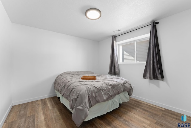 bedroom featuring visible vents, baseboards, and wood finished floors