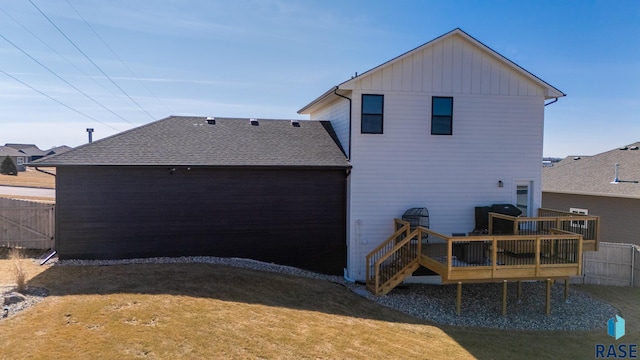 rear view of house with fence, roof with shingles, a yard, a deck, and board and batten siding