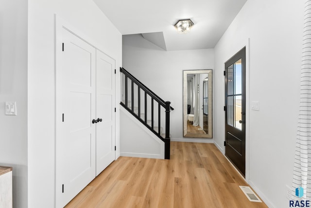 entryway featuring light wood-type flooring, visible vents, baseboards, and stairs