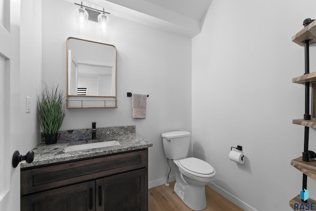 bathroom with vanity, toilet, wood finished floors, and baseboards