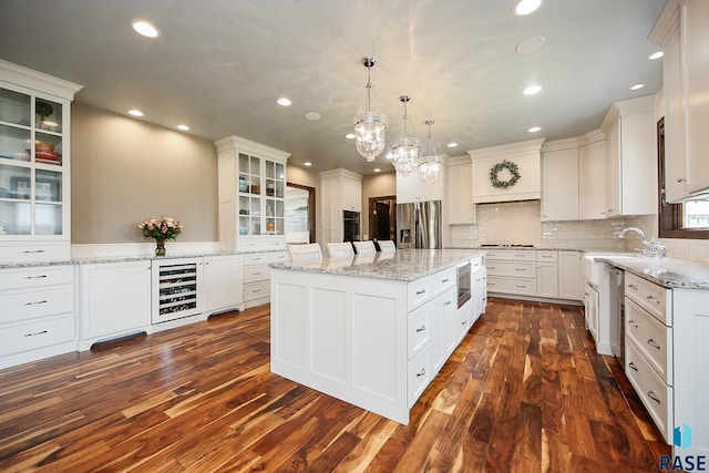 kitchen featuring a kitchen island, wine cooler, stainless steel appliances, dark wood-style floors, and white cabinetry