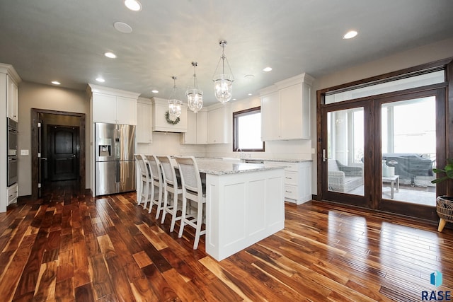 kitchen featuring a kitchen island, an inviting chandelier, dark wood-style flooring, stainless steel appliances, and white cabinets