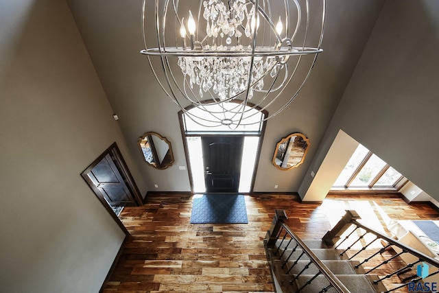 entrance foyer featuring baseboards, wood finished floors, a high ceiling, and a chandelier