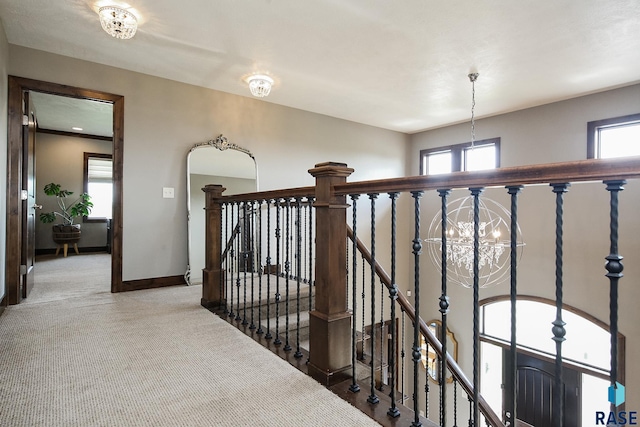 hallway featuring an upstairs landing, light carpet, baseboards, and a wealth of natural light