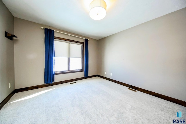 carpeted empty room featuring baseboards and visible vents