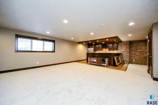 unfurnished living room featuring visible vents, light carpet, recessed lighting, brick wall, and baseboards