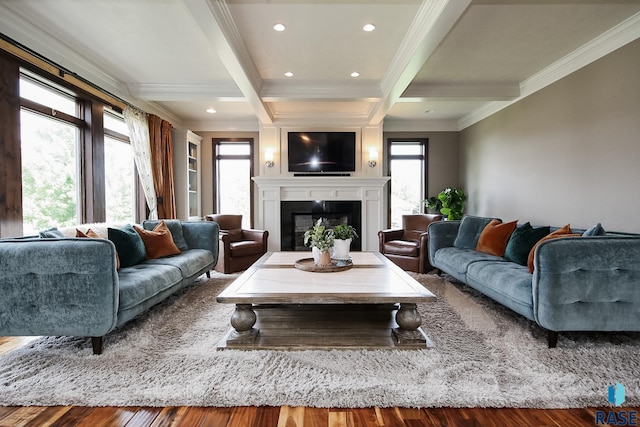 living area with wood finished floors, coffered ceiling, beam ceiling, crown molding, and a large fireplace