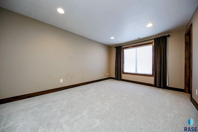 spare room featuring light carpet, visible vents, recessed lighting, and baseboards