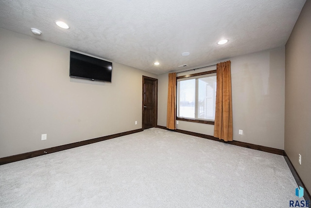 unfurnished room with a textured ceiling, recessed lighting, baseboards, and light carpet