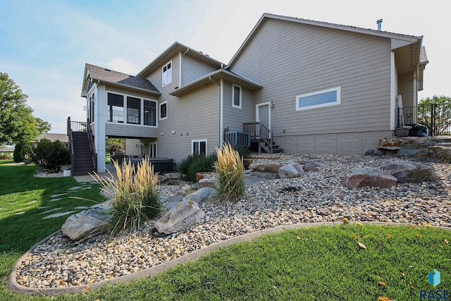 back of property with stairs, central AC unit, a lawn, and a sunroom