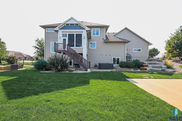 back of house with a sunroom, a lawn, stairs, and a hot tub