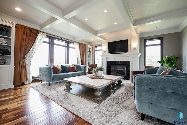 living area featuring beam ceiling, coffered ceiling, a large fireplace, and wood finished floors