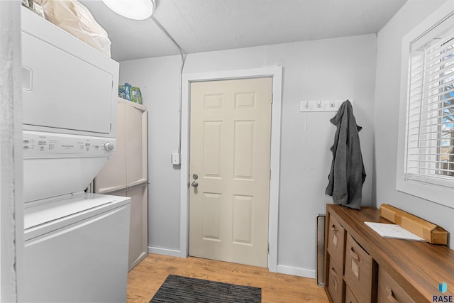 laundry room featuring light wood-type flooring, baseboards, laundry area, and stacked washing maching and dryer