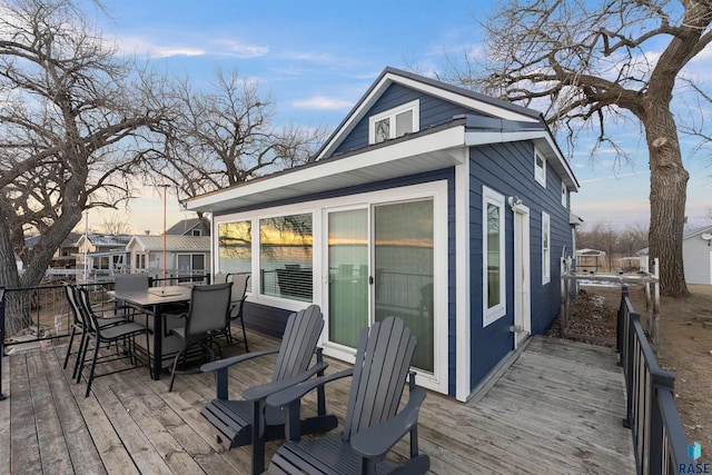 deck at dusk featuring outdoor dining space